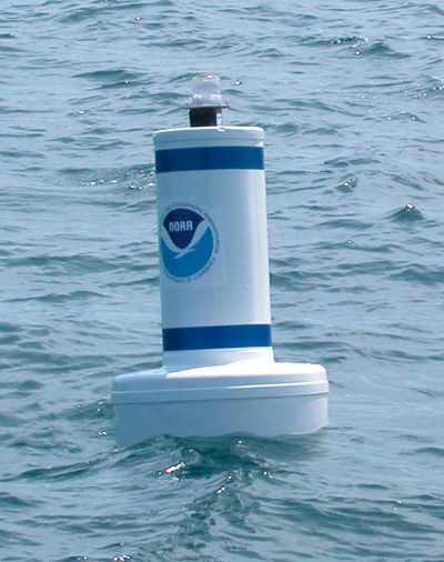 a white buoy with the national oceanic and atmospheric administration logo floats at the surface of the water