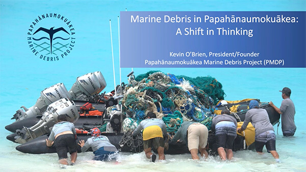 Volunteers in Papahānaumokuākea pushing boat filled with discarded nets and debris with blue box and white text reading “Marine Debris in Papahānaumokuākea: A Shift in Thinking,” “Kevin O’Brien, Prescient/Founder, Papahānaumokuākea Marine Debris Project (PMDP)”.