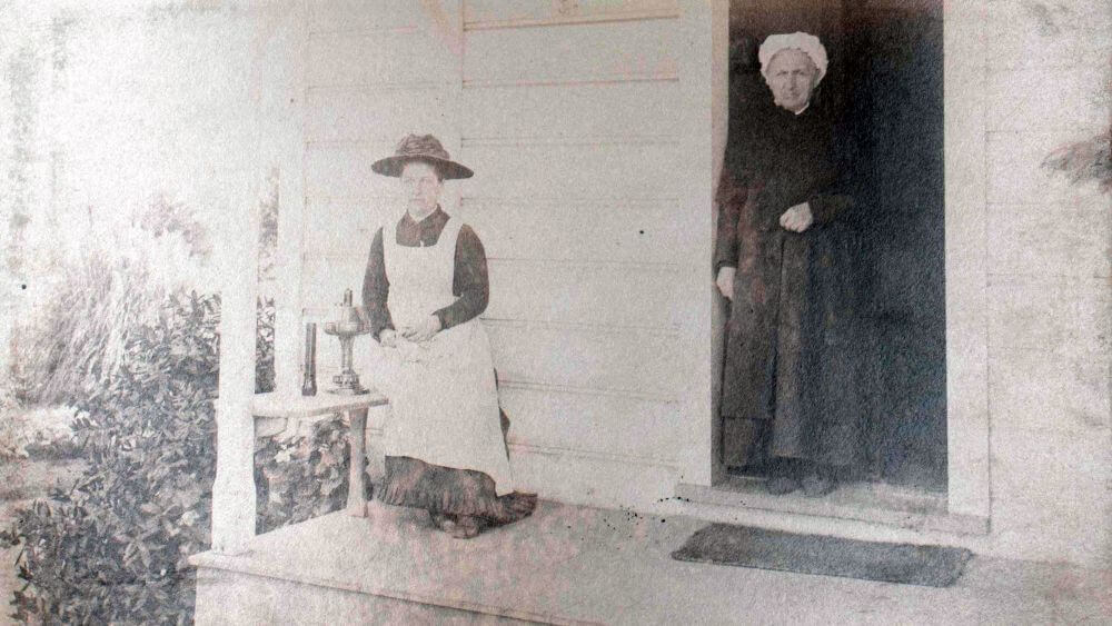 two people posing on the front porch of keeper's house