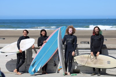 Queer Surf team members posing with their boards on the beach