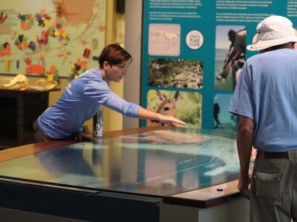 a person points at a large map on an exhibit table