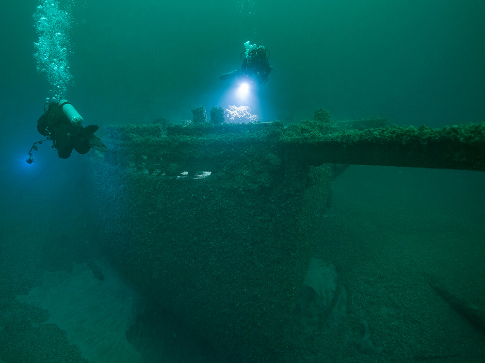 Divers examine the bow of a shipwreck