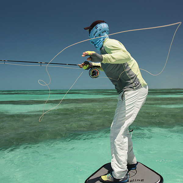 person standing on a boat fly fishing