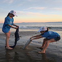 two kids removing marine debris from the beach