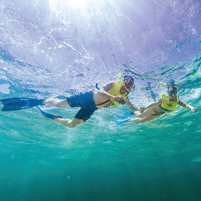 A man and women snorkeling and taking underwater photos