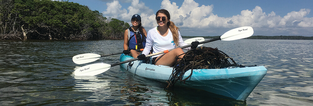 Two women on a kayak with marine debris