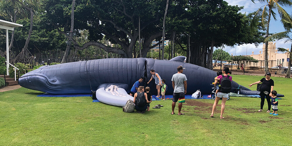 Children and their parents observing an inflatable whale
