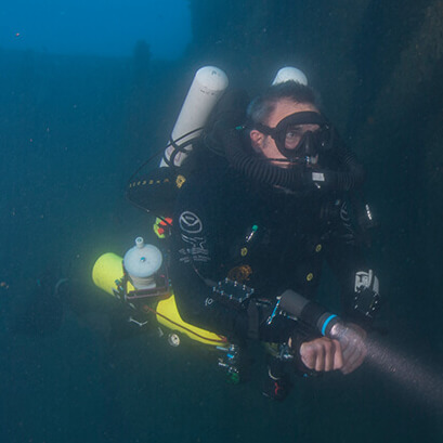 A diver points his flashlight forward