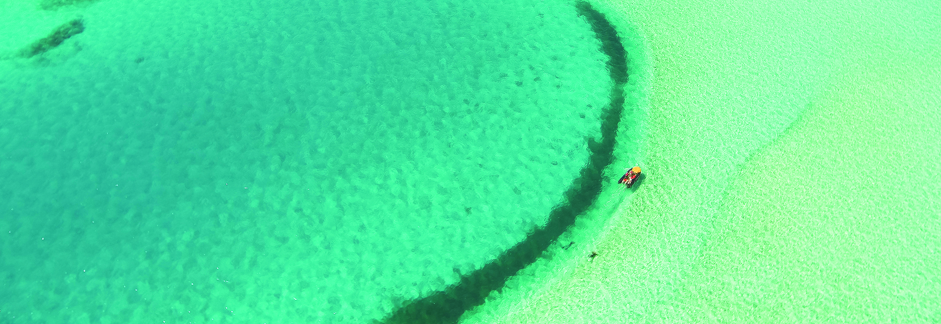 An aerial shot of a boat in crystal clear waters