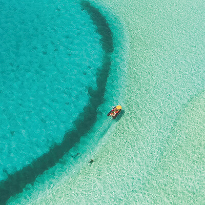 An aerial shot of a boat in crystal clear waters