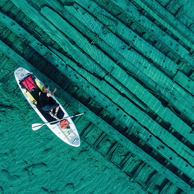 Aerial shot of a paddleboarder over a shipwreck in shallow water