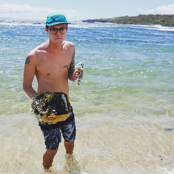 A man holds marine debris on a beach