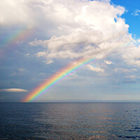 A rainbow extends over the ocean