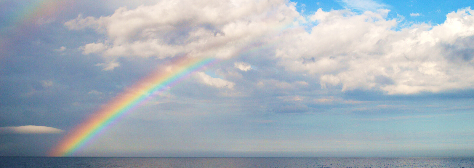 A rainbow extends over the ocean
