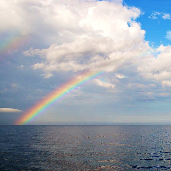 A rainbow extends over an ocean