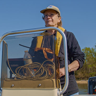 a woman stands at the steering wheel of a boat