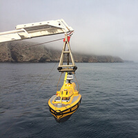 A yellow rov extended over water by a crane