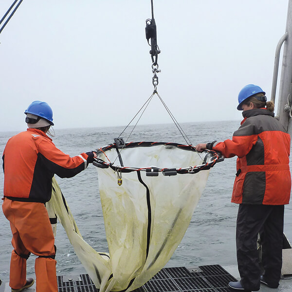 Two pwople handle a net on the deck of a ship