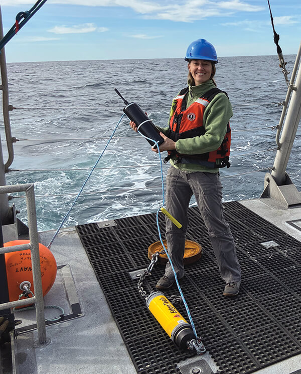 a person stands on the deck of a ship with sound monitoring equipment