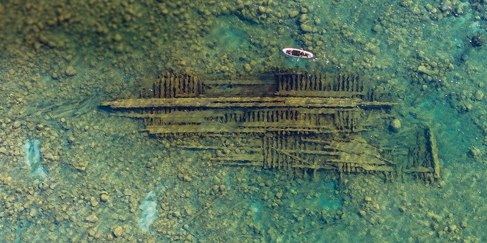 aerial view of a paddleboard paddling past a shipwreck