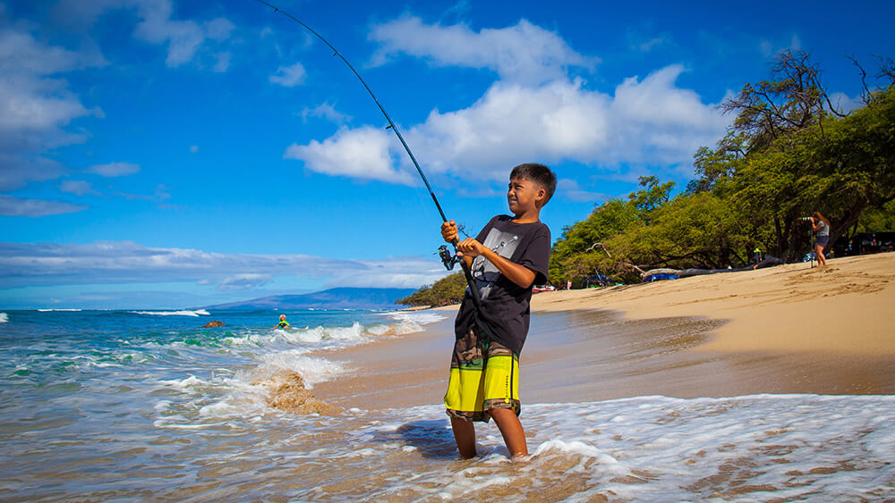 A child fishes from the beach in Hawaiian Islands Humpback Whale National Marine Sanctuary