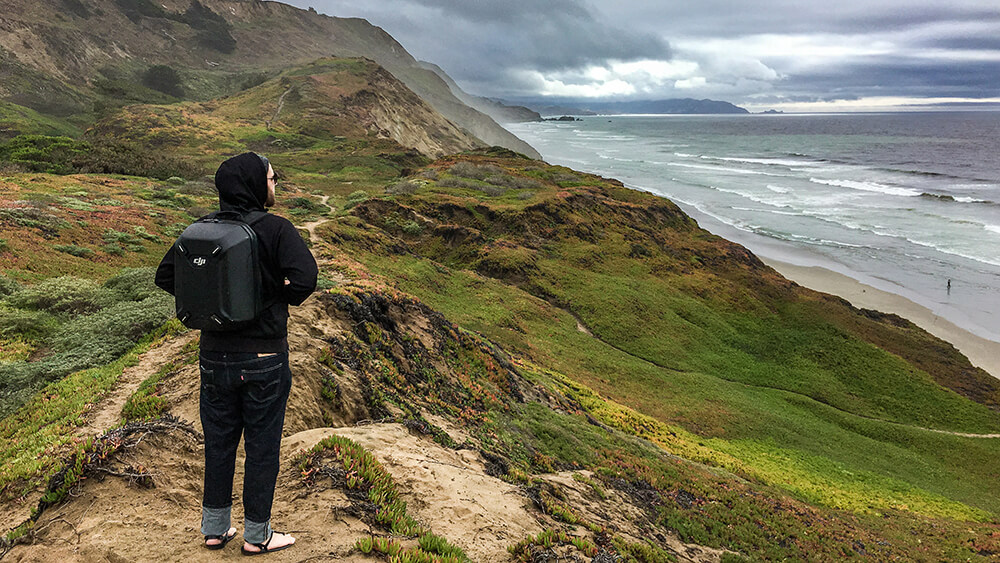 A hiker looks down to the ocean in front of him