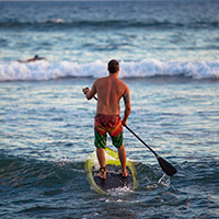 A stand up paddleboarder heads out into the waves of Hawaiian Islands Humpback Whale National Marine Sanctuary