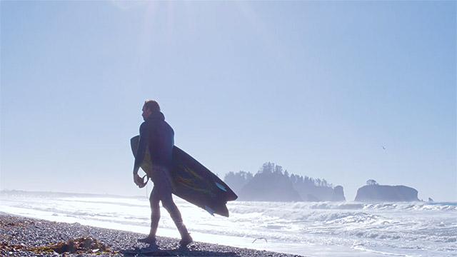 surfer with board in hand walking on the beach
