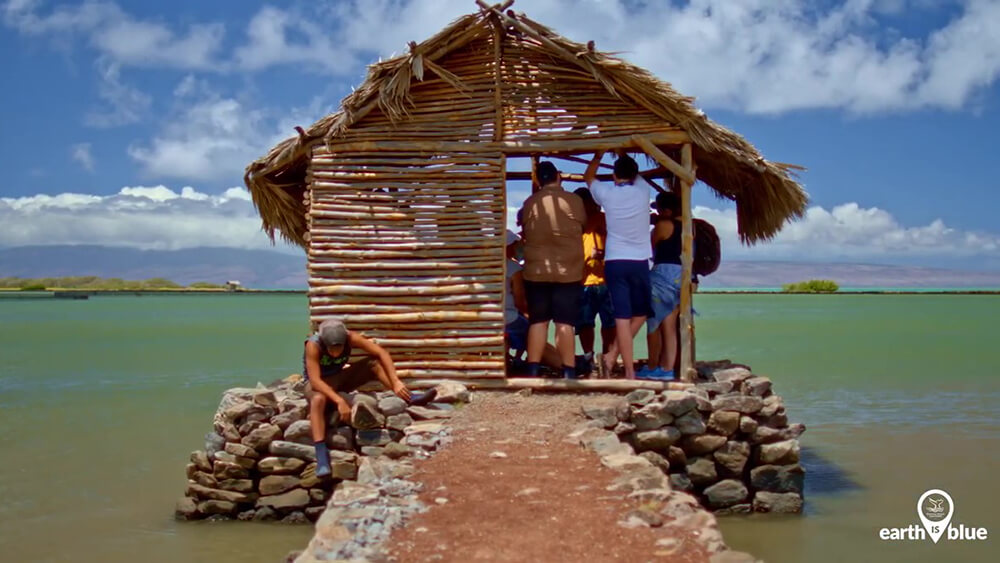 People work on a small hut near the ocean