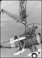 A Sparrowhawk hangs for the trapeze of USS Macon during flight operations in 1933.