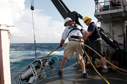 two people deploying an rov off a ship