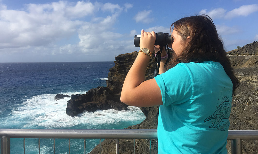 woman using binoculars to look out to sea