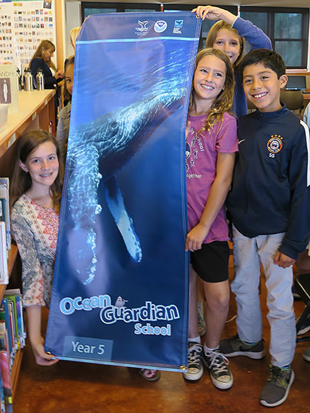 students holding up an ocean guardian banner celebrating their fifth year