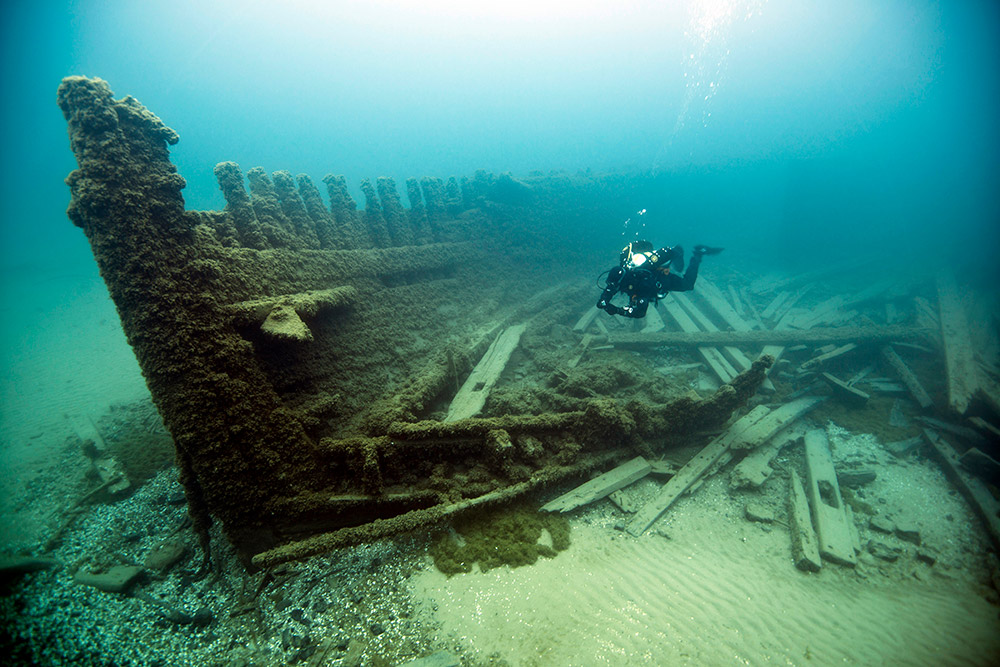 a diver swims in front of the Lucinda Van Valkenburg shipwreck