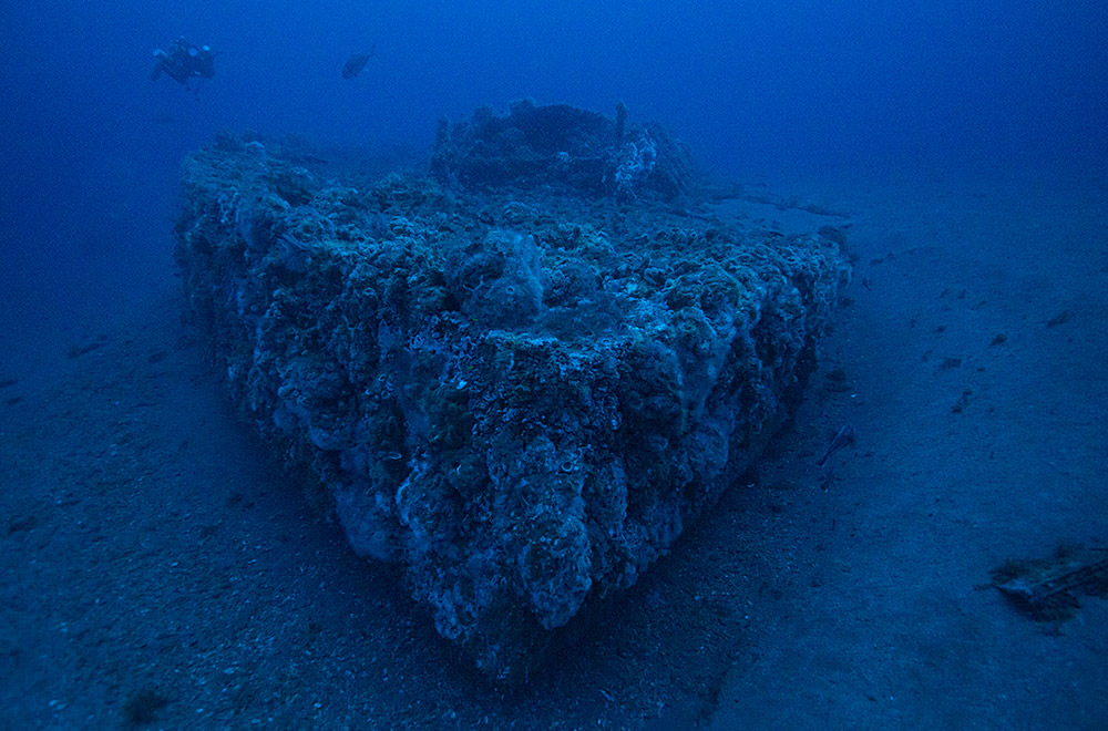 view of the wreck of uss monitor under water. a diver is swimming near by