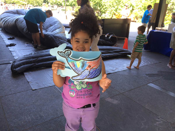 kid holding a whale hat that she colored in