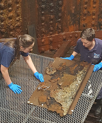 Conservators inspect one the pieces of a nut guard from the turret