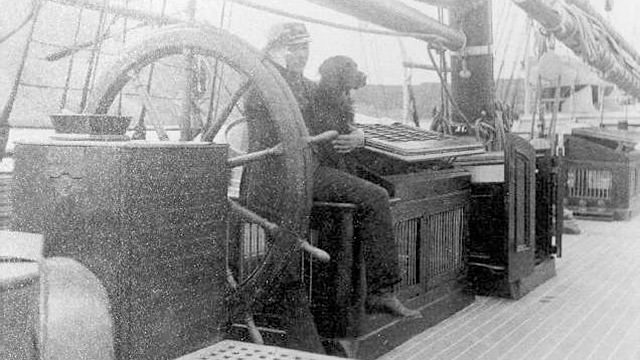 Captain Michael A. Healy with a dog sitting at the wheel of the steam cutter bear