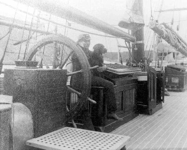 Captain Michael A. Healy with a dog sitting at the wheel of the steam cutter bear