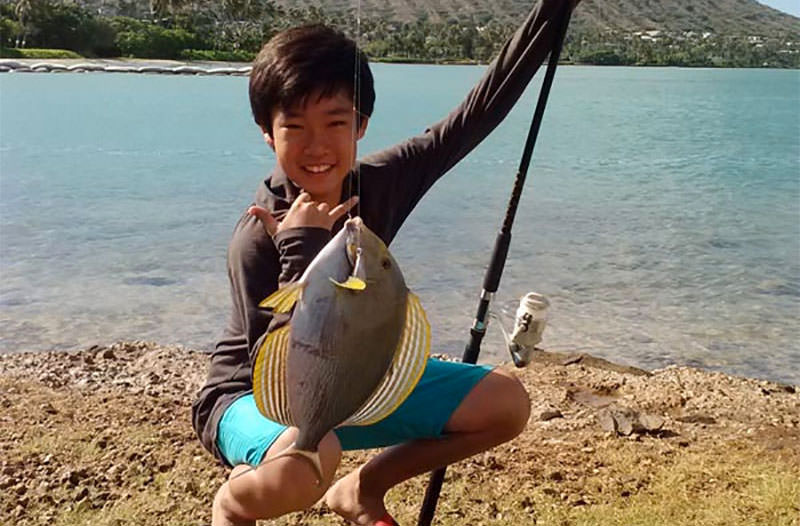 photo of a kid holding up a fish he caught