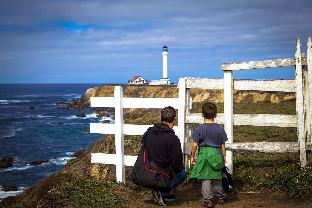 father and son looking at point arena lighthouse in the distance