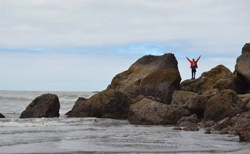 photo of gabe almario standing on rocks near the ocean
