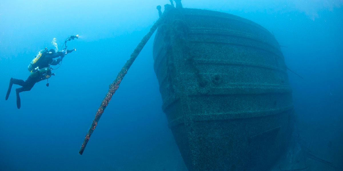 a diver takes a photo of a shipwreck