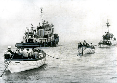 MV Fernstream survivors; officers, crewmen and passengers in lifeboats under tow by U.S. Coast Guard cutter while a U.S. Army tug stands by