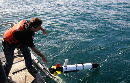Cyril Poissonnett of Teledyne SeaBotix deploying AUV to conduct side scan sonar survey of shipwreck Ituna. Credit: Denise Jaffke for NOAA