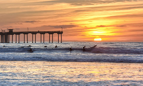 sunset and surfers on ocean beach